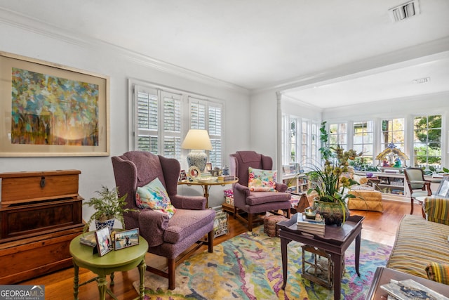 living room featuring ornamental molding, wood finished floors, and visible vents