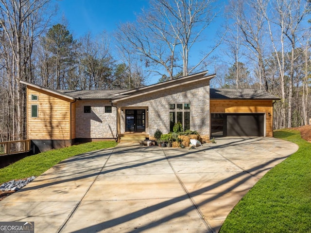 mid-century home with a garage, stone siding, and concrete driveway