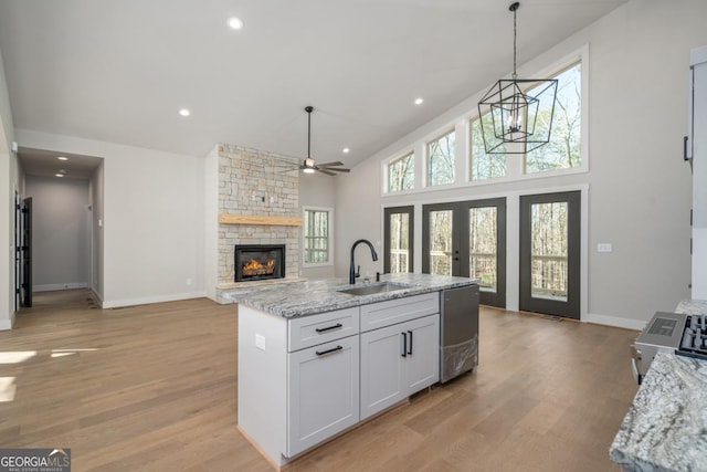 kitchen with light wood-type flooring, dishwasher, white cabinetry, and a sink