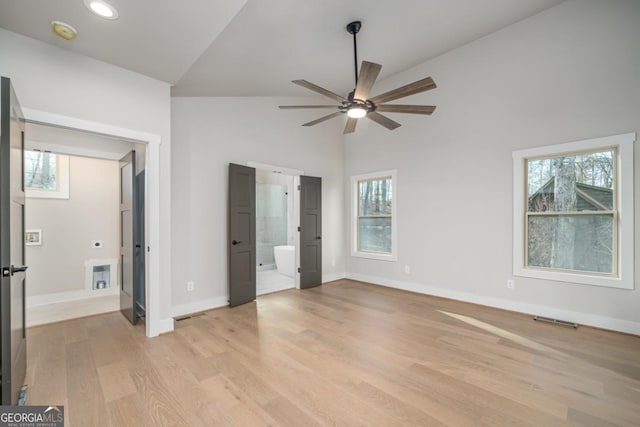 unfurnished bedroom featuring light wood finished floors, visible vents, baseboards, ensuite bath, and high vaulted ceiling