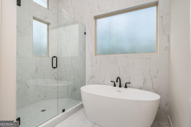 full bathroom featuring marble finish floor, a freestanding tub, and a marble finish shower