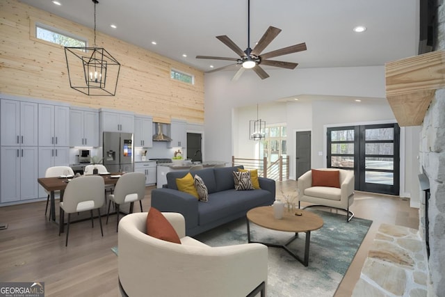 living room with a wealth of natural light, light wood-type flooring, wooden walls, and a high ceiling