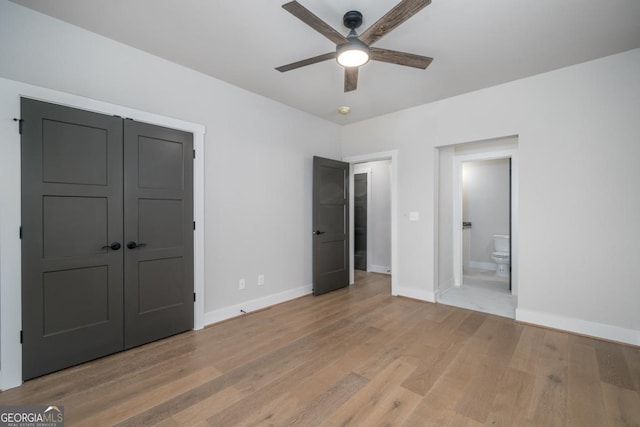 unfurnished bedroom with ceiling fan, connected bathroom, light wood-style flooring, and baseboards