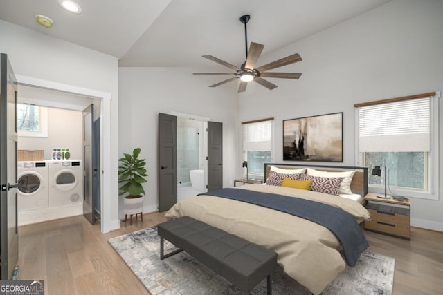 bedroom with light wood-style floors, washing machine and dryer, high vaulted ceiling, and ensuite bathroom