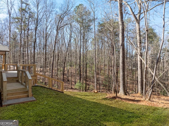 view of yard with a wooded view and a wooden deck