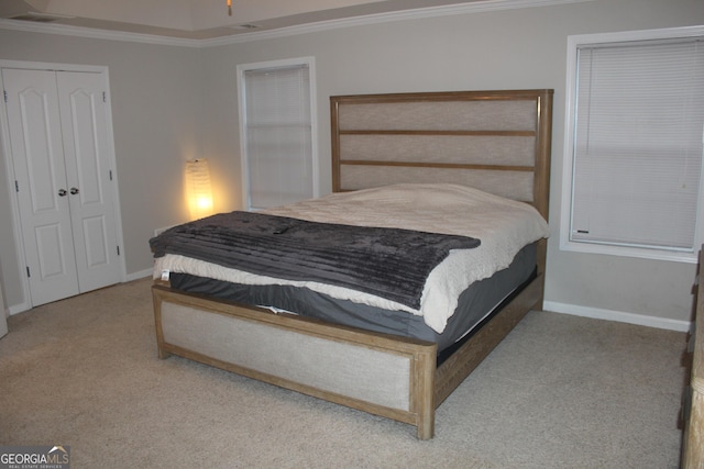 carpeted bedroom with a closet, baseboards, and crown molding