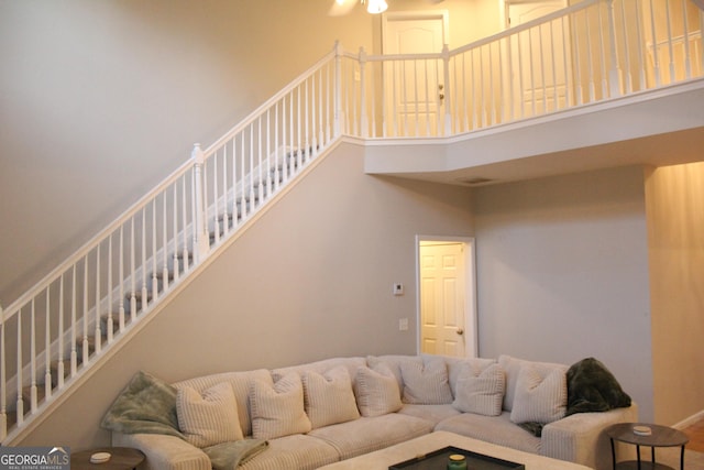 living area with stairway and a towering ceiling