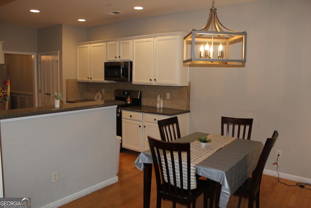 dining space with recessed lighting, a notable chandelier, wood finished floors, visible vents, and baseboards