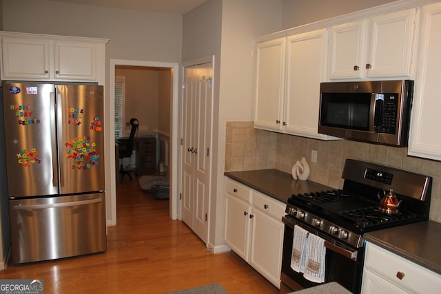 kitchen featuring dark countertops, appliances with stainless steel finishes, and white cabinets