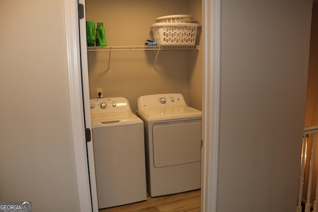 laundry area with laundry area, washing machine and dryer, and light wood finished floors