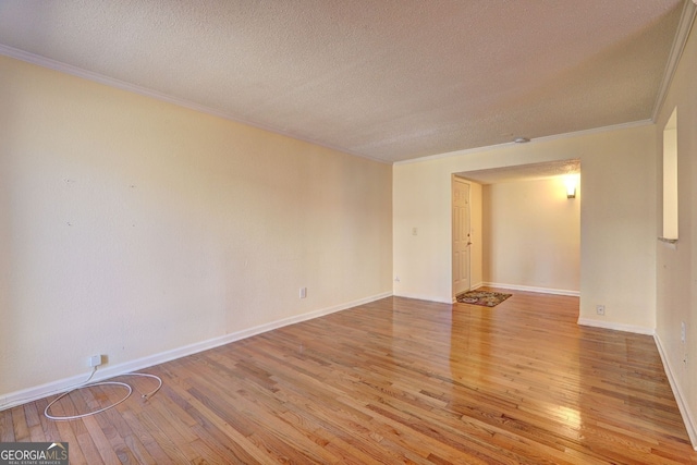 unfurnished room featuring baseboards, ornamental molding, a textured ceiling, and light wood-style floors