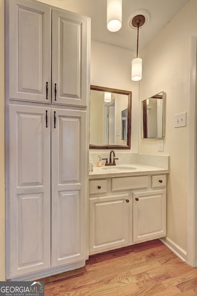 bathroom with baseboards, wood finished floors, and vanity