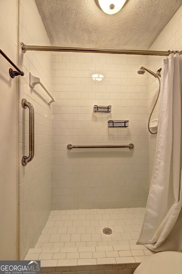 full bathroom featuring a textured ceiling, a stall shower, and toilet