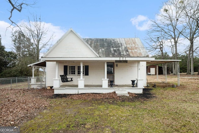 view of front facade with covered porch, fence, metal roof, and a carport