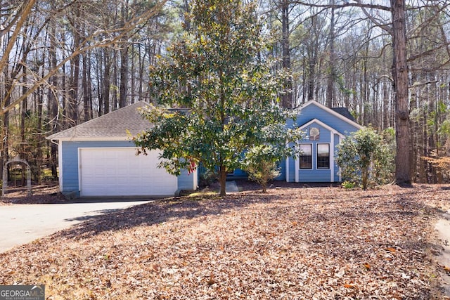 view of front of property with concrete driveway, a shingled roof, and an attached garage