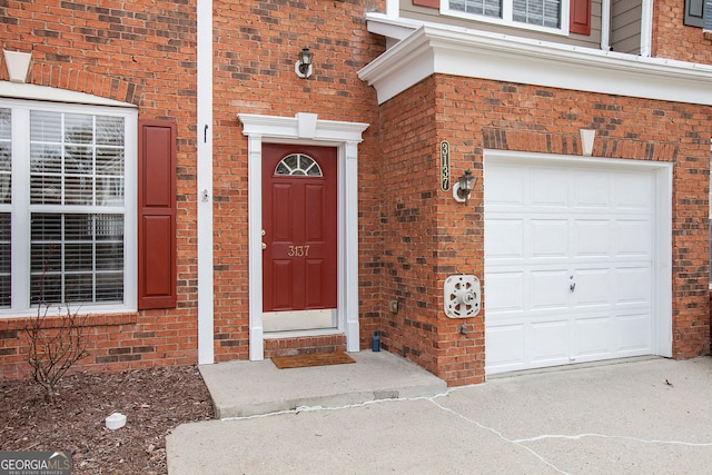 property entrance with brick siding and an attached garage