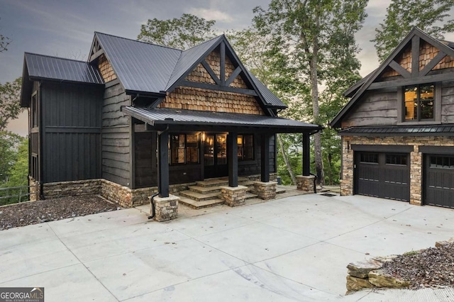 view of front of home featuring a garage, stone siding, and metal roof