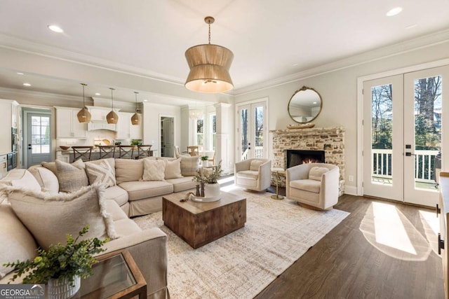 living room featuring a warm lit fireplace, recessed lighting, french doors, dark wood finished floors, and crown molding