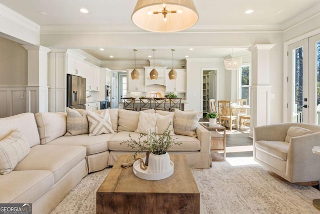 living area with ornate columns, crown molding, wainscoting, and a decorative wall