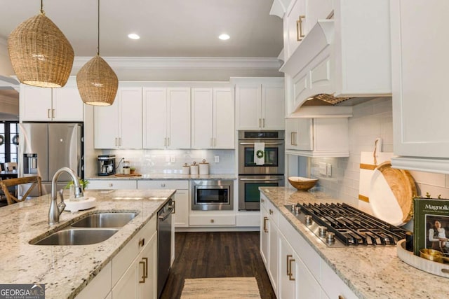 kitchen with appliances with stainless steel finishes, a sink, white cabinets, and crown molding