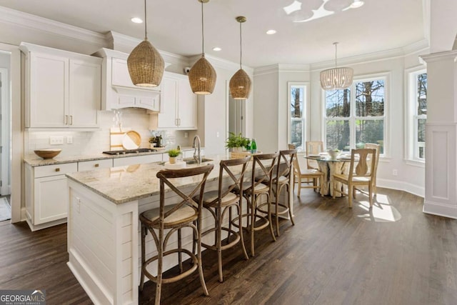 kitchen with stainless steel gas stovetop, dark wood-type flooring, backsplash, and white cabinets