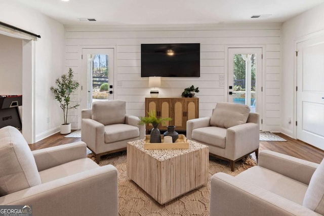 living room with light wood finished floors, a wealth of natural light, visible vents, and baseboards