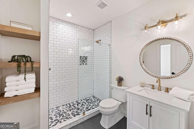 full bathroom with visible vents, toilet, tile patterned floors, a tile shower, and vanity