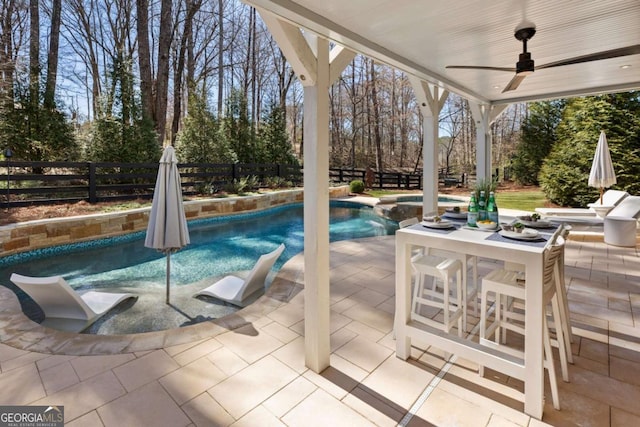 view of swimming pool featuring ceiling fan, a fenced backyard, a pool with connected hot tub, outdoor dining space, and a patio area