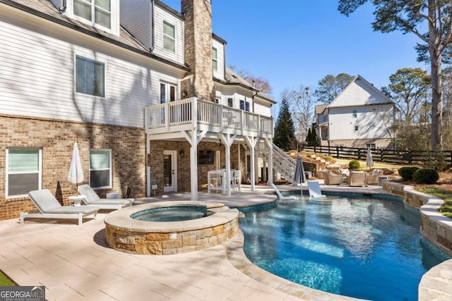 view of pool with a deck, a patio, fence, a pool with connected hot tub, and stairs