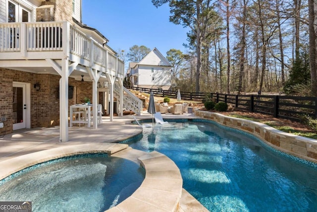 view of pool with a pool with connected hot tub, a patio area, a fenced backyard, and stairs