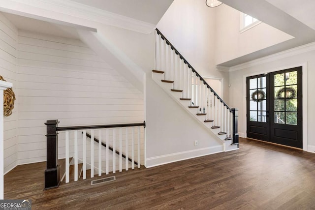 entryway featuring a towering ceiling, visible vents, wood finished floors, and ornamental molding