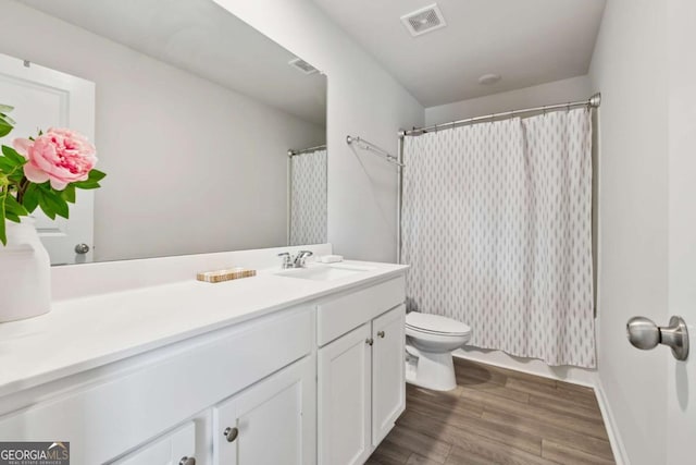 bathroom with visible vents, vanity, toilet, and wood finished floors