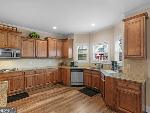 kitchen featuring brown cabinetry, light wood-style flooring, appliances with stainless steel finishes, and a sink