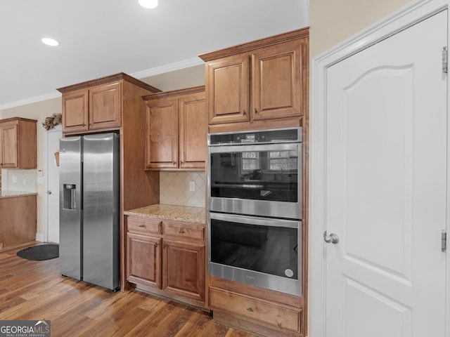 kitchen with wood finished floors, appliances with stainless steel finishes, and ornamental molding