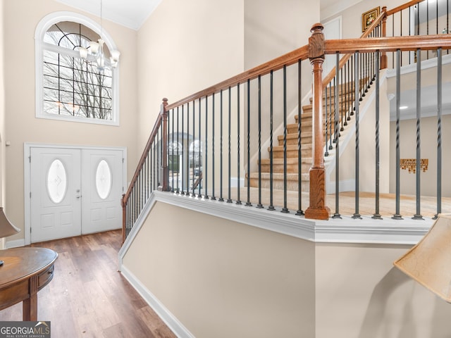 entryway with baseboards, stairway, wood finished floors, an inviting chandelier, and a towering ceiling