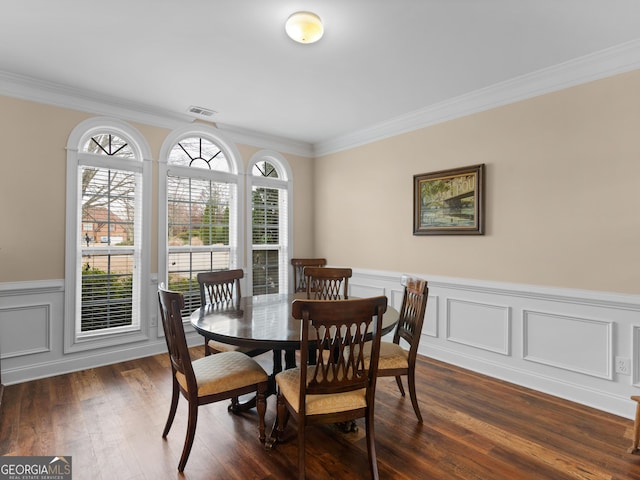 dining area with dark wood-style floors, visible vents, wainscoting, and ornamental molding