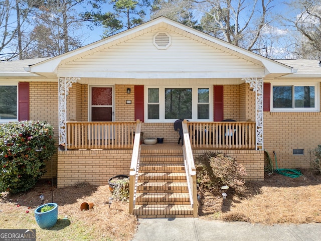 view of front of home with crawl space, a porch, and brick siding