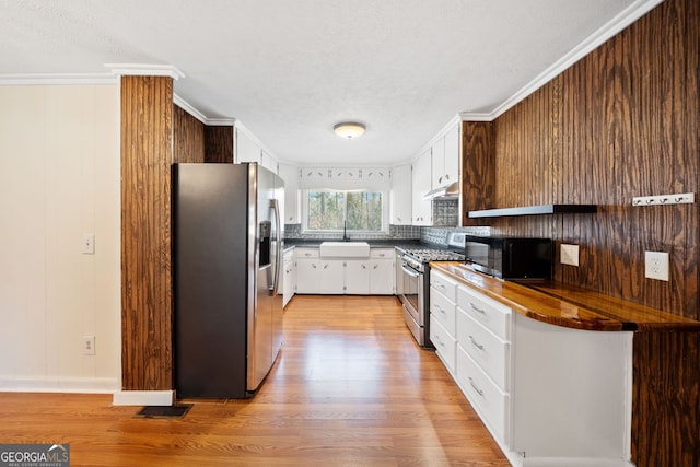 kitchen featuring ornamental molding, stainless steel appliances, light wood-type flooring, under cabinet range hood, and a sink