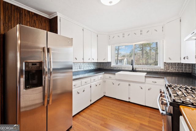 kitchen featuring appliances with stainless steel finishes, dark countertops, a sink, and backsplash