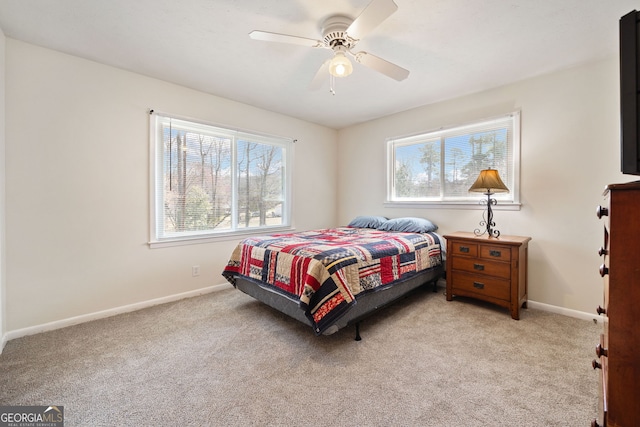 bedroom with light carpet, multiple windows, a ceiling fan, and baseboards