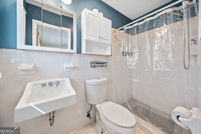 full bath featuring a sink, a tile shower, tile walls, and toilet