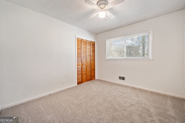 unfurnished bedroom with ceiling fan, carpet flooring, visible vents, baseboards, and a closet