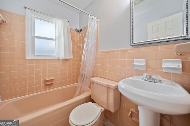 full bath featuring a wainscoted wall, shower / tub combo with curtain, tile walls, visible vents, and toilet