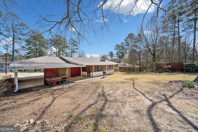 rear view of property featuring a yard, driveway, and a chimney