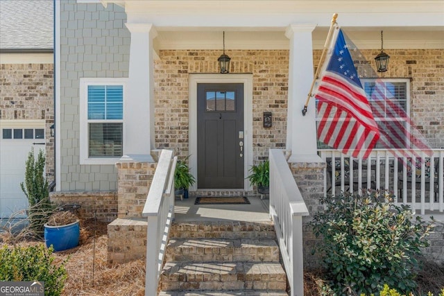 doorway to property featuring a porch and brick siding