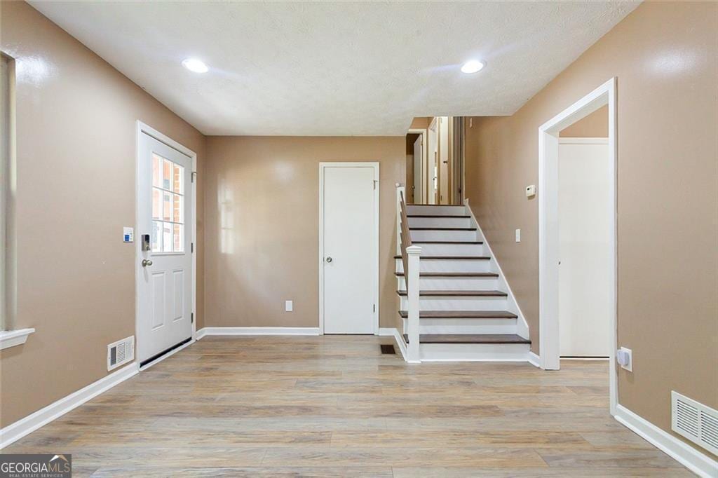 foyer featuring light wood-type flooring, visible vents, and baseboards