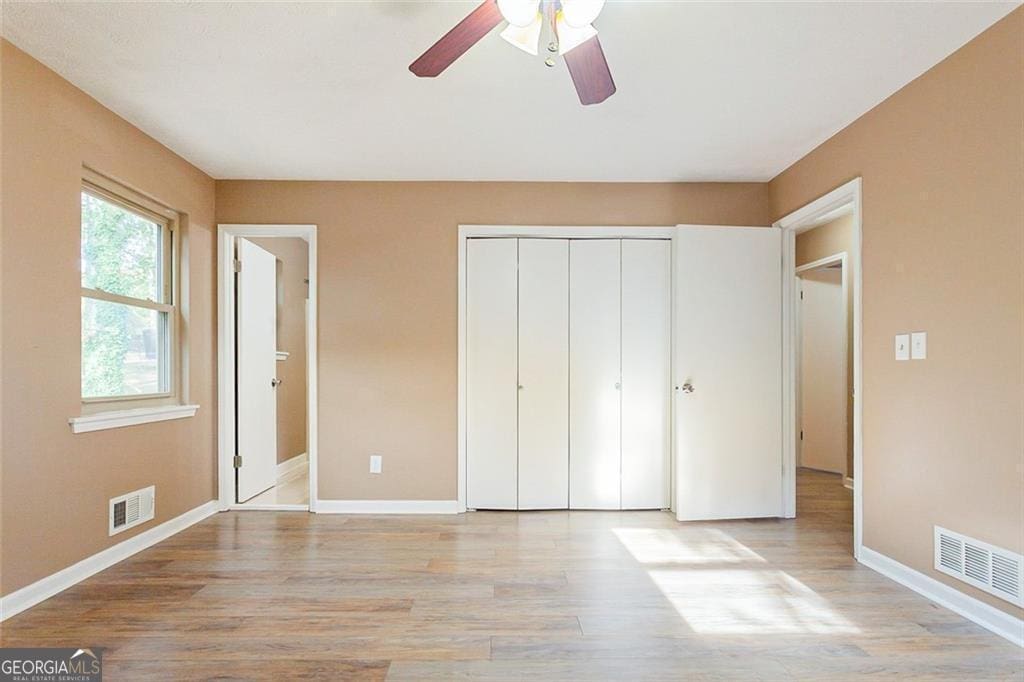 unfurnished bedroom with light wood finished floors, a closet, visible vents, and baseboards