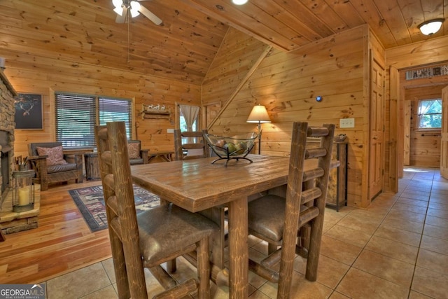 dining area with vaulted ceiling, wooden ceiling, wood walls, and light tile patterned floors