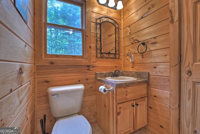 bathroom with wood walls, vanity, and toilet