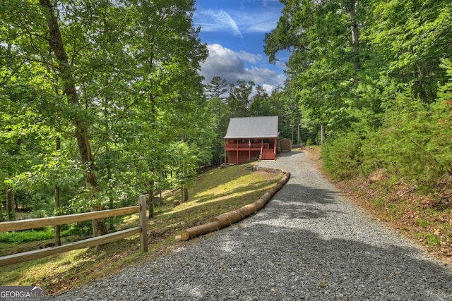 chalet / cabin featuring gravel driveway, fence, and a wooded view